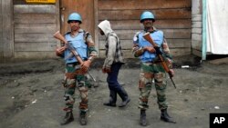 Deux soldats de la mission des Nations unies au Congo patrouillent à côté d'un passant à Goma, RDC.