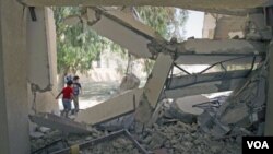 Dua anak Libya bermain di reruntuhan gedung, yang menurut Tripoli adalah sebuah gedung sekolah yang hancur akibat serangan NATO (4/8).