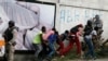 FILE - Members of the press take cover as clashes with police break out at the end of an anti-government march called by the artist community in Port-au-Prince, Haiti, Oct. 20, 2019.