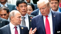FILE - U.S. President Donald Trump and Russia's President Vladimir Putin talk during the family photo session at the APEC Summit in Danang, Vietnam, Nov. 11, 2017. 