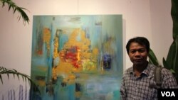 លោក ឈឹម​ សុធី​ ជា​វិចិត្រករ​ដ៏​មាន​បទ​ពិសោធ​យូរ​ឆ្នាំ​ ឈរ​នៅ​មុខ​គំនូរ​របស់​លោក​ ដែល​ត្រូវ​បាន​ដាក់​បង្ហាញ​ក្នុង​ពិព័រណ៌​ «Consuming Passion»​ ក្នុង​​សណ្ឋាគារ​ ក្នុង​រាជធានី​ភ្នំពេញ​ កាល​ពី​ថ្ងៃ​ទី​២៥​ ខែ​មិថុនា​ ឆ្នាំ​២០១៥។​ ពិព័រណ៌​គំនូរ​នេះ​អំពាវនាវ​ឲ្យ​មាន​ការថែរក្សា​បរិស្ថាន​និង​ធនធាន​ធម្មជាតិ​នៅ​ក្នុង​ប្រទេស​កម្ពុជា​ (នូវ​ ពៅ​លក្ខិណា/VOA)