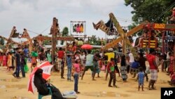 ស្ត្រី​ជន​ជាតិរ៉ូហ៊ីងយ៉ា​ម្នាក់​កំពុង​អង្គុយ​ក្រោម​ឆ័ត្រ​ដើម្បី​លក់​​ផ្លែ​ឈើ​នៅ​កន្លែង​លេង​ក្នុង​ជំរំ​ Kutupalong ក្នុង​ប្រទេស​បង់ក្លាដែស កាល​ពី​ថ្ងៃទី​២៣ សីហា ២០១៨។