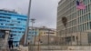 ARCHIVO - La bandera estadounidense ondea junto a un agente de seguridad que custodia la embajada de Estados Unidos en La Habana, Cuba, el 12 de diciembre de 2023. 