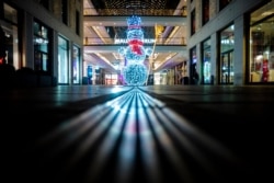 Un hombre de nieve iluminado a la entrada de un vacío Mall de Berlín, el miércoles 16 de diciembre de 2020 por la noche en la capital alemana, cuando el país entró a un cierre más restrictivo por el COVID-19.