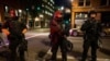 Policías de armados con fusiles de guerra mantienen la vigilancia en Portland, Oregon, durante protestas en agosto.