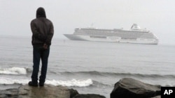 FILE - A man stands on the Bering Sea shore looking at the luxury cruise ship Crystal Serenity anchored just outside Nome, Alaska, Aug. 21, 2016.