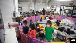 Niños no acompañados, de entre 3 y 9 años de edad, permanecen un corral de plástico mientras son procesados para su ubicación desde Donna, Texas, el 30 de marzo de 2021.