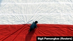 Seorang pria mempersiapkan bendera raksasa sebelum mengibarkannya pada perayaan hari kemerdekaan di Universitas Kristen Petra di Surabaya, Jawa Timur. Pemerintah mungkin akan menawarkan kewarganegaraan ganda bagi orang-orang keturunan Indonesia. (Foto: REUTERS/Sigit Pamungkas)