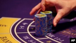FILE - a croupier counts the chips at a baccarat gaming table inside a casino during the opening day of Sheraton Macao Hotel at the Sands Cotai Central in Macau.