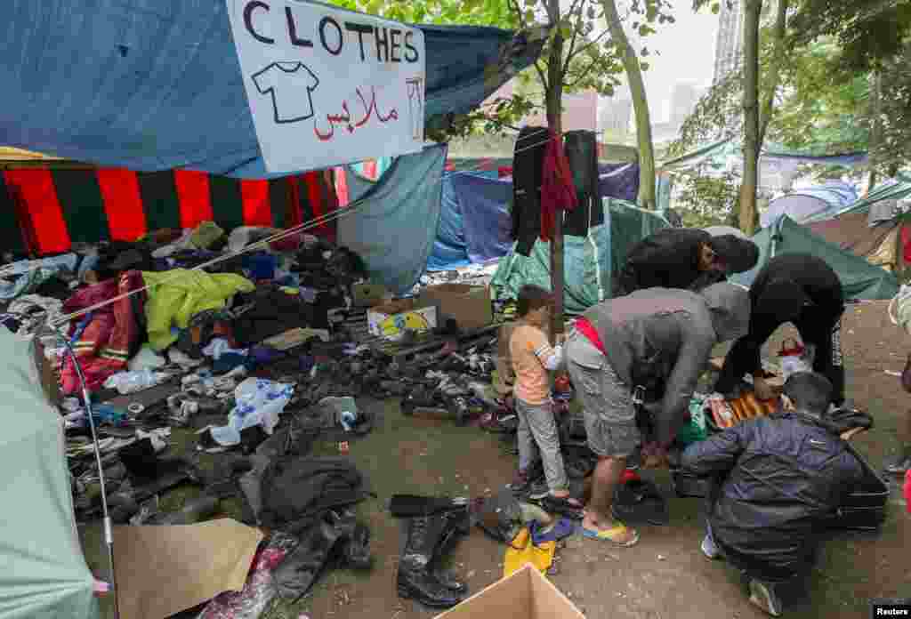 Para pencari suaka mencari pakaian di tempat penampungan sementara di luar kantor luar negeri di Brussels, Belgia (3/9). Sekitar 2.300 orang meminta suaka di Belgia bulan Juni saja, naik sepertiga dari bulan sebelumnya, menurut data resmi. Pemerintah Belgia telah menawarkan perumahan untuk 2.500 pendaftar tambahan. (Reuters/Yves Herman)