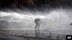 Protester tries to evade spray from police water cannon, Santiago, Chile, June 25, 2015.