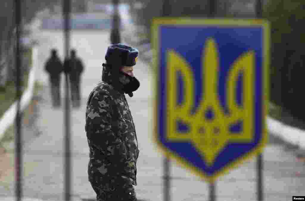 Seorang tentara Ukraina berjalan di dekat sebuah pintu gerbang tertutup di sebuah pangkalan angkatan udara Krimea di Belbek, 20 Maret 2014.