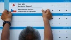A volunteer builds the scoreboard for the beach volleyball match that was ultimately canceled because one player, Marketa Slukova of the Czech Republic, tested positive for COVID-19, at Shiokaze Park, Tokyo, Japan, July 24, 2021.