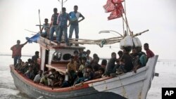 An Acehnese fishing boat full of rescued migrants approaches to dock in Simpang Tiga, Aceh province, Indonesia, Wednesday, May 20, 2015. Hundreds of migrants stranded at sea for months were rescued and taken to Indonesia, officials said Wednesday, the lat