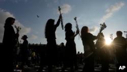 ARCHIVO - Las mujeres sostienen flores y caminan entre cajas que representan ataúdes simbólicos mientras recuerdan a exguerrilleros y líderes sociales que han sido asesinados desde la firma de un acuerdo de paz en 2016, en Bogotá, Colombia, el martes 20 de febrero de 2024.
