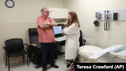 In this July 9, 2019 photo, Dr. Jori Fleisher, neurologist, examines Thomas Doyle, 66, at the Rush University Medical Center in Chicago. Doyle, 66, hopes blood tests may someday replace the invasive diagnostic testing he endured to be diagnosed 4.5 years 