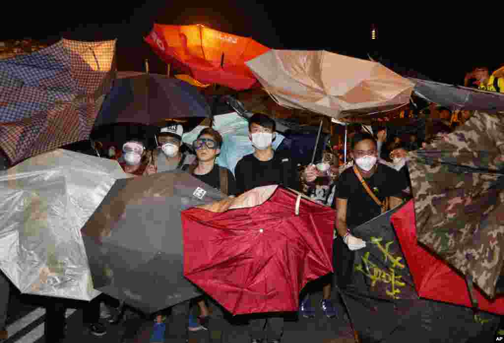 Para demonstran menggunakan payung untuk menghindari air merica yang disemprotkan oleh polisi di luar kantor-kantor pemerintahan Hong Kong di daerah Admiralty (15/10). (AP Photo/Kin Cheung)