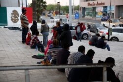 FILE - Migrants recently expelled from the U.S. after trying to seek asylum sit next to the international bridge in the Mexican border city of Reynosa, March 27, 2021.