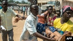 Une victime d'un échange des tirs portée par des hommes qui la conduisent à l'hôpital à Bangui, le 13 décembre 2015. (AFP / LUCA SOLA)