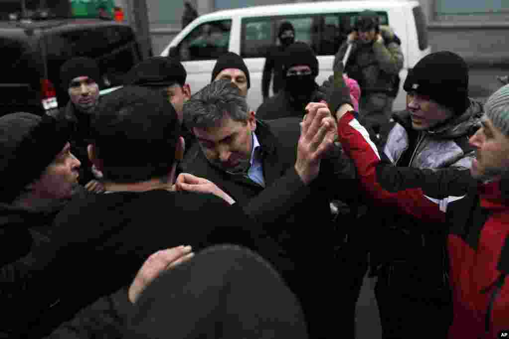 A suspected supporter of Ukraine's embattled President Viktor Yanukovych, center, is assaulted by anti-government protesters in Kyiv.