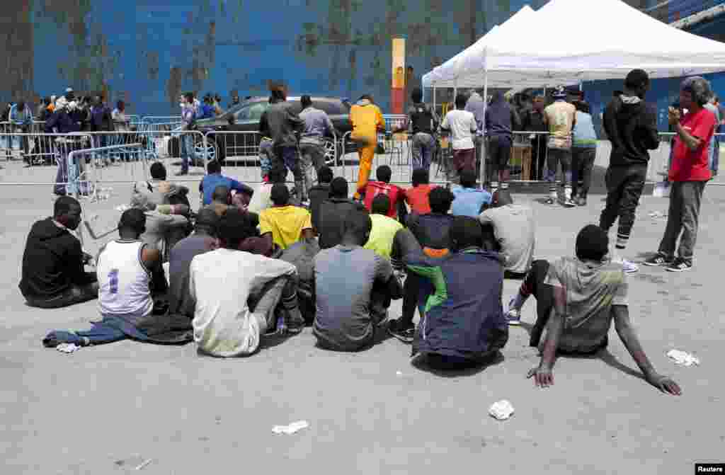 Groups of migrants wait after disembarking from a merchant ship at the Sicilian harbor of Catania, southern Italy, May 5, 2015. 