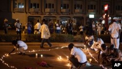 Des Burkinabès allumant des bougies lors d'une cérémonie commémorative pour les victimes de la récente attaque djihadiste à Ouagadougou, le 23 janvier 2016.