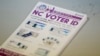 FILE - A pile of government pamphlets explaining North Carolina's controversial "Voter ID" law sits on table at a polling station, July 15, 2016.