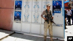 FILE - An Iraqi Turkoman fighter stands guard outside the Iraqi Turkmen Front headquarters in Kirkuk, Iraq, June 16, 2014.