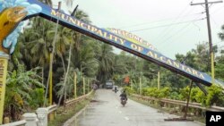 Motorists drive past a fallen marker that was toppled by Tropical Storm Jangmi at Alcantara township, Cebu province, central Philippines, Dec. 30, 2014.