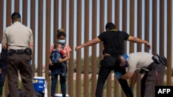 Agentes de la Patrulla Fronteriza de Estados Unidos revisan y registran a los migrantes de Guatemala después de que se entregaran a las autoridades en la frontera entre Estados Unidos y México, el 12 de mayo de 2021 en Yuma, EE. UU.