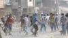 FILE - Cambodia garment workers throw stones at riot police during a strike near a factory on the Stung Meanchey complex on the outskirts of Phnom Penh, Cambodia, Friday, Jan. 3, 2014.