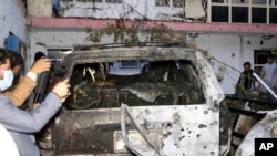 Wartawan Afghanistan mengambil foto kendaraan yang hancur di dalam sebuah rumah setelah serangan pesawat tak berawak AS di Kabul, Afghanistan, Minggu, 29 Agustus 2021. (Foto: AP)