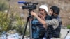 El periodista de AFPTV, Nicolás García Ferrari (izq.), filma con su colega Saleh Hamad en una posición en Ramallah, en la Cisjordania ocupada, el 20 de octubre de 2023, en medio de las batallas en curso entre Israel y el movimiento palestino Hamas.
