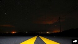 Lights from Waimea, Hawaii, shine in the distance as wildfires burn in the area, Aug. 5, 2021. The region was scorched by the state's largest-ever wildfire.