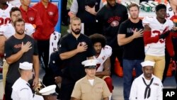 San Francisco 49ers quarterback Colin Kaepernick, middle, kneels during the national anthem before the team's NFL preseason football game against the San Diego Chargers, Thursday, Sept. 1, 2016.