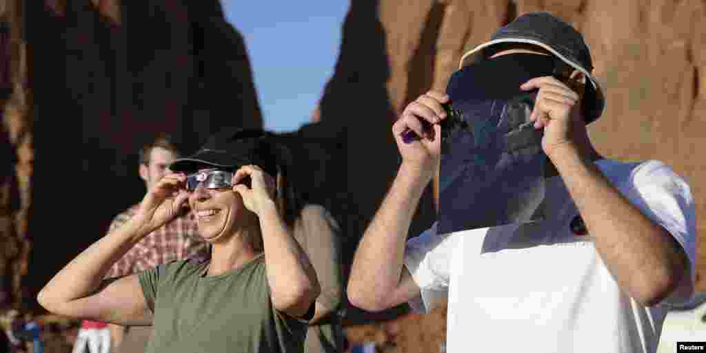 Turistas miran a través de gafas protectoras el eclipse anular desde el Parque Valley Tribal Park en Utah.