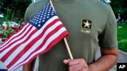 A Pakistani recruit, 22, who was recently discharged from the U.S. Army, holds an American flag as he poses for a picture, July 3, 2018. 