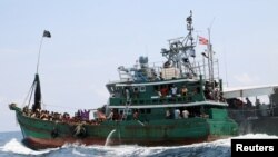 Un bateau avec des migrants est remorqué par un navire de la marine thaïlandaise, dans les eaux proches de l'île de Koh Lipe le 16 mai 2015. 