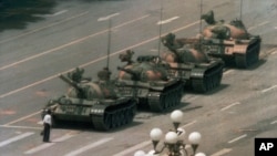 Seorang pria China tampak sendiri berupaya menahan barisan tank yang menuju ke arah timur di Alun-alun Tiananmen, awal Juni 1989. 