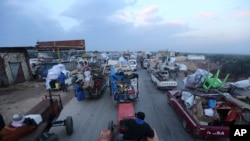 Truckloads of civilians flee a Syrian military offensive in Idlib province on the main road near Hazano, Syria, Dec. 24, 2019. Syrian forces launched a wide ground offensive last week into the northwestern province of Idlib.