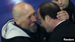 Presiden Perancis Francois Hollande (kanan) dan bekas tawanan al-Qaida Africa Utara yang baru saja dibebaskan, Serge Lazarevic, saling berpelukan seusai menyampaikan sambutan di bandara militer Villacoublay dekat Paris (10/12).