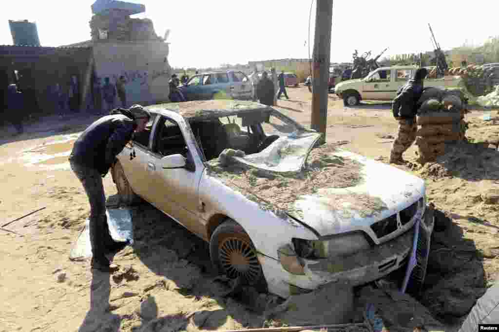 A man looks at a damaged car near a military base 50 km outside Benghazi, after a suicide bomber detonated a truck packed with explosives at an army checkpoint, Barsis, Libya, Dec. 22, 2013. 
