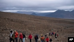 People climb to the top of what once was the Okjokull glacier, in Iceland, Aug. 18, 2019.