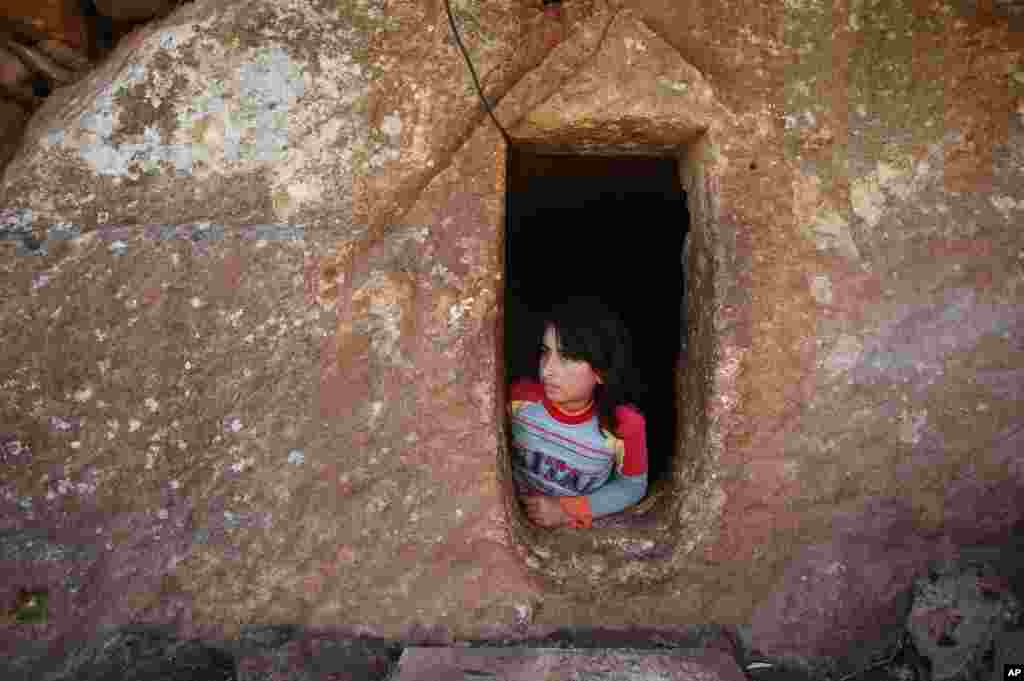 Nihal, 9, looks at the entrance of an underground Roman tomb used as shelter from Syrian government shelling and airstrikes, Jabal al-Zaweya, Idlib province, Syria, Feb. 28, 2013.