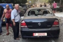 Un hombre herido camina junto a un auto dañado en una calle, luego de la explosión en Beirut.