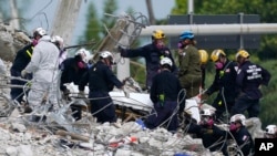 Tim SAR memindahkan jenazah korban yang ditemukan di lokasi bangunan kondominium Champlain Towers South yang runtuh, di Surfside, Florida, dengan tandu, 5 Juli 2021.