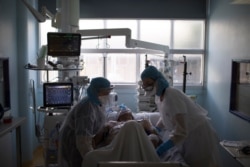 Healthcare workers assist a COVID-19 patient in the intensive care unit at the Joseph Imbert Hospital Center in Arles, southern France, April 5, 2020.