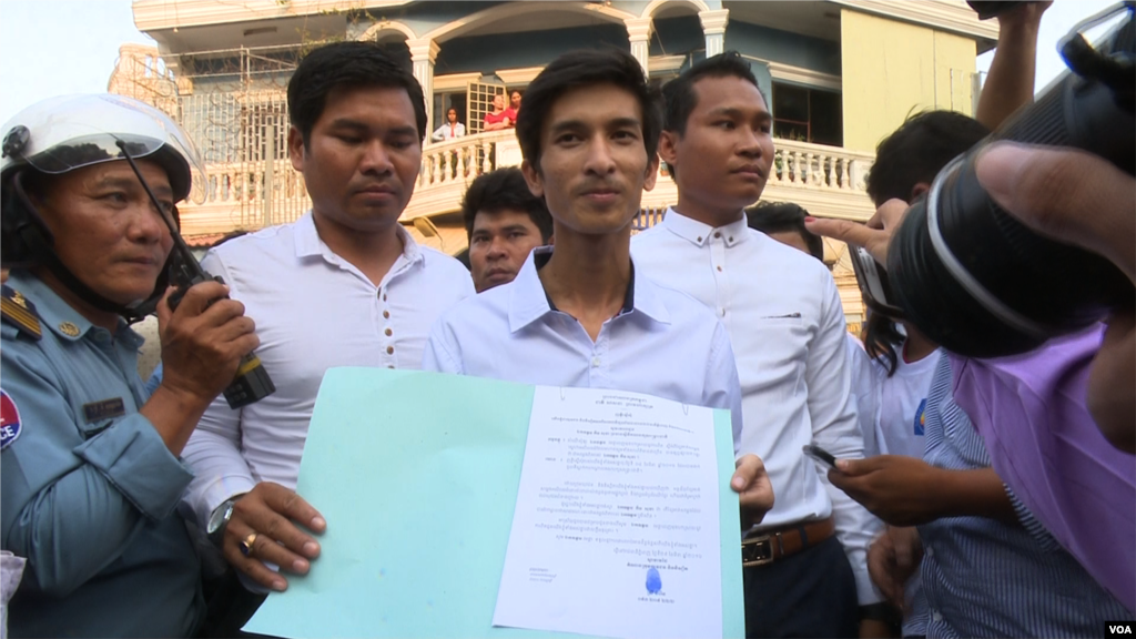 Srey Chamroeun, who led students group dressing in CNRP's uniform, shows his petition to journalists. (Leng Len/VOA Khmer). 