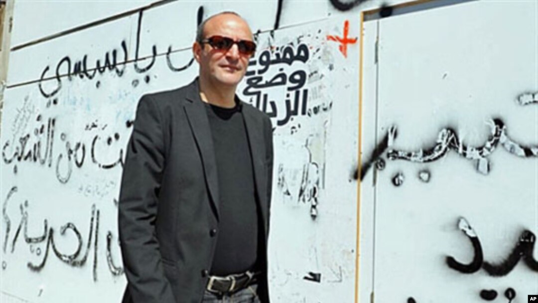 Tunisian director Mourad Cheikh walks past a wall covered with graffiti in Tunis, ahead of the screening of his documentary 'No More Fear' - a 74-minute documentary filmed in the midst of the uprising that led to Tunisian President Zine el Abidine Ben Ali