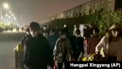 En esta imagen extraída de un video y publicada por Hangpai Xingyang, gente con maletas sale de un complejo de Foxconn en Zhengzhou, en la provincia central china de Henan, el sábado 29 de octubre de 2022. 